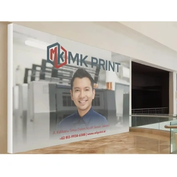 Banner promosi MK Print dengan gambar pria tersenyum di depan mesin cetak, logo MK Print, alamat kantor, dan nomor telepon bisnis.