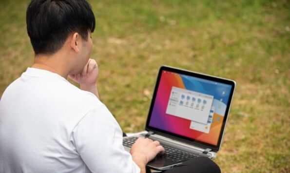 Cara Membuat Desain Banner untuk Pemula 1 seseorang sedang duduk dan membuka laptop untuk belajar cara membuat desain banner