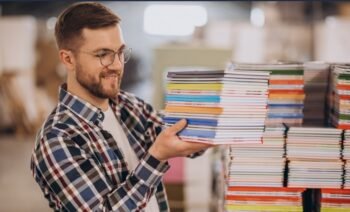 seorang sedang membawa buku bertumpuk menggambarkan tip memilih jasa cetak buku