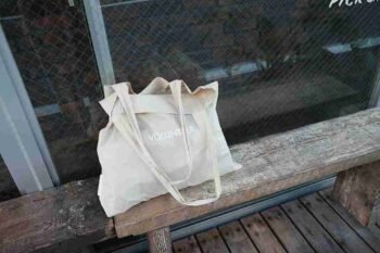 Blog 19 Totebag custom volunteer warna krem di atas bangku kayu, cocok untuk kegiatan sosial atau branding komunitas.
